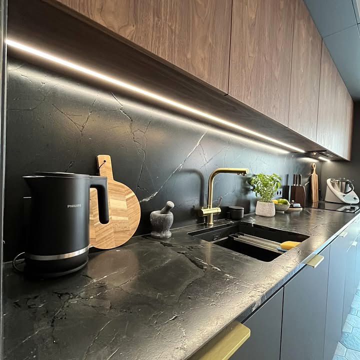 Kuchnia z ciemnym spiekiem, drewnianymi frontami i mosiężną baterią